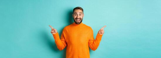 Shopping and advertisement concept. Excited man buyer pointing fingers sideways, showing two choices products, left and right banners, standing over light blue background photo