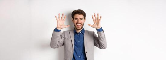 Frustrated man giving up, raising hands up in surrender and screaming, having argument, wearing suit and looking distressed, white background photo