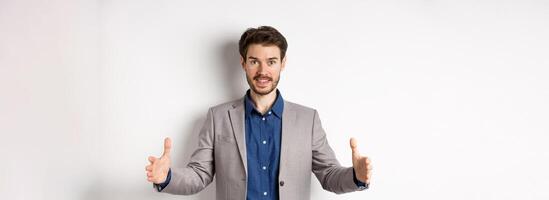 Excited handsome businessman showing long size thing, big object with stretch out hands, standing in suit on white background photo