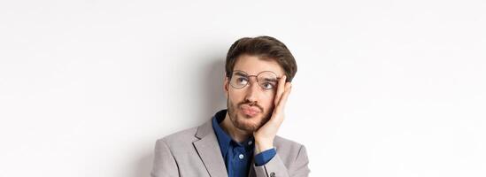 Close-up of shocked tired office worker takes-off glasses and stare at upper right corner with sad face, white background photo