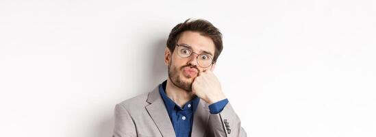 Bored funny office worker in glasses, pouting and holding breath, staring with popped eyes at camera, white background photo