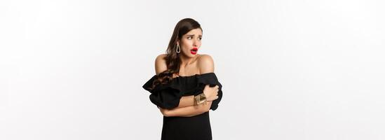 Image of scared and shocked glamour woman looking around, comfort herself, standing alarmed against white background photo