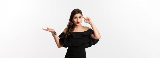 Fashion and beauty. Annoyed and bothered woman pointing at head, scolding someone for stupid mistake, looking confused, standing over white background photo