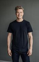 A portrait of a man in a black t-shirt and jeans, standing against a neutral grey background. photo