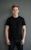 A portrait of a man in a black t-shirt and jeans, standing against a neutral grey background. photo