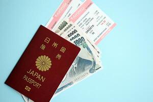 Japan passport with money and airline tickets on blue background close up photo