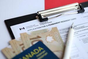 Application for permanent resident card on table with pen and canadian passport with money photo