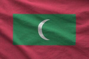 Maldives flag depicted on folded wavy fabric of old cloth photo