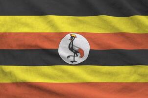 Uganda flag depicted on folded wavy fabric of old cloth photo