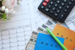 Japanese pension insurance booklets on table with yen money bills and calculator on table photo