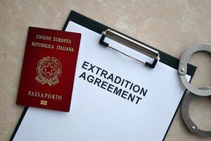 Passport of Italy and Extradition Agreement with handcuffs on table photo