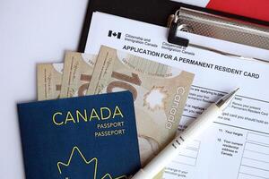 Application for permanent resident card on table with pen and canadian passport with money photo