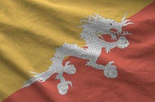 Bhutan flag depicted on folded wavy fabric of old cloth photo