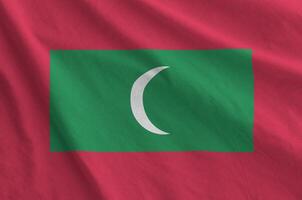 Maldives flag depicted on folded wavy fabric of old cloth photo