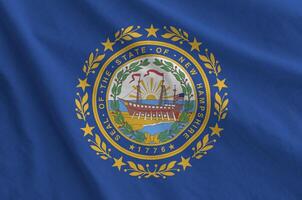 New Hampshire US state flag depicted on folded wavy fabric of old cloth photo