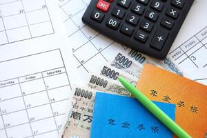 Japanese pension insurance booklets on table with yen money bills and calculator on table photo