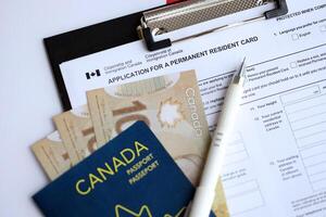 Application for permanent resident card on table with pen and canadian passport with money photo