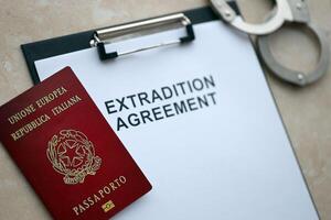 Passport of Italy and Extradition Agreement with handcuffs on table photo