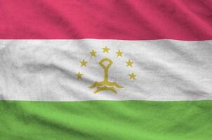 Tajikistan flag depicted on folded wavy fabric of old cloth photo