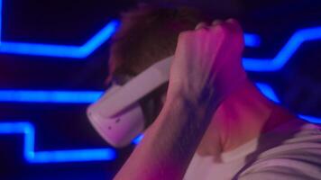 A man plays a VR game in a neon room. video
