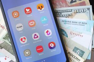 KYIV, UKRAINE - FEBRUARY 28, 2024 Dating apps icons on smartphone display and money bills photo