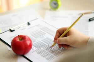 Female student hands testing in exercise and taking fill in exam paper sheet with pencil at school test photo