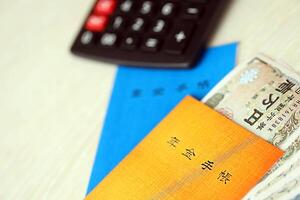 Japanese pension insurance booklets on table with yen money bills and calculator on table photo