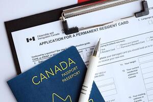 Application for permanent resident card on table with pen and canadian passport photo