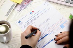KYIV, UKRAINE - OCTOBER 31, 2023 Accountant fill french tax form CA12 Value added tax and similar taxes in end of tax period. Taxation and paperwork routine photo