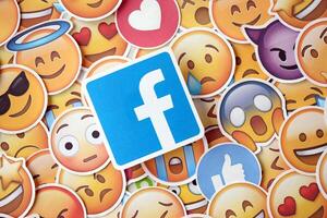 KYIV, UKRAINE - APRIL 20, 2024 Facebook logo and large set of stickers with Emoji yellow faces. Emoji is a pictogram or smiley embedded in text and used in electronic messages photo