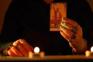 KYIV, UKRAINE - JULY 10, 2024 Tarot reader picking tarot cards. Candlelight in dark room. Tarot reader or fortune teller reading and forecasting photo