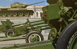Photo of three guns of the Soviet Union of the Second World War against the background of the green tank T-34