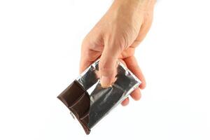 Hand holds a bar of chocolate isolate close-up photo