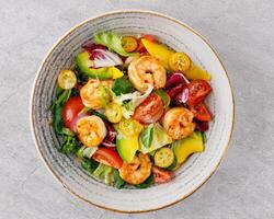 Salad with shrimps in sweet and sour sauce with mango and avocado. on a gray background photo