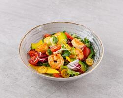 Salad with shrimps in sweet and sour sauce with mango and avocado. on a gray background photo