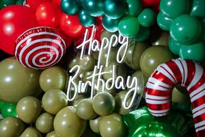 A neon sign with a green and red striped cactus and a green and red striped candy cane with the words Happy Birthday written on it photo