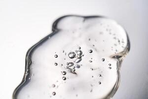 A smear of cosmetic gel close-up on a gray background. Appetizing texture with bubbles. photo