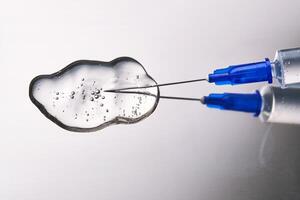 A drop of medicine flowing from a syringe with a needle. photo