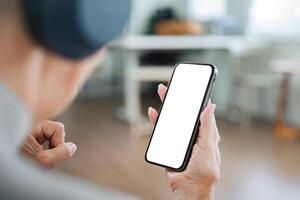Senior Woman Using Smartphone with Blank Screen at Home, Close-Up View of Hand Holding Mobile Device photo