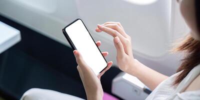 Woman Using Smartphone on Airplane with Blank Screen for Mockup, In-flight Technology and Connectivity photo