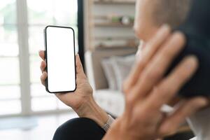 Man Holding Smartphone with Blank Screen While Sitting Indoors Near Window in Modern Home photo