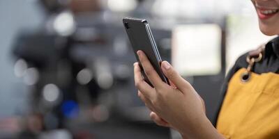 Young Barista Using Smartphone in Modern Cafe, Close up of Hands Holding Mobile Device, Technology and Communication Concept photo