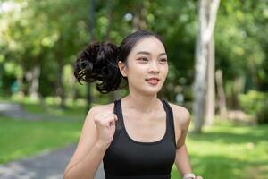 Young Woman Jogging in Park on a Sunny Day, Wearing Sportswear, Staying Fit and Healthy, Enjoying Outdoor Exercise, Green Trees in Background photo