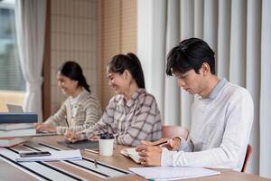 Group of Focused Student Studying Together in a Modern Classroom Setting with Laptops and Notebooks photo