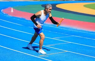 Senior Asian athlete is practicing running in the professional blue track for professional exercise, sport training workout and healthy for longevity concept photo