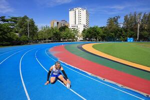 Senior Asian athlete doing stretching warm up for running in the professional blue track for professional exercise, sport training workout and healthy for longevity concept photo