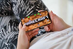 Minecraft mobile iOS game on iPhone 15 smartphone screen in female hands during mobile gameplay photo