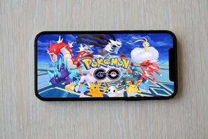 Pokemon GO mobile iOS game on iPhone 15 smartphone screen on wooden table during mobile gameplay photo