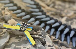 Ukrainian symbol and a machine gun belt on the camouflage uniform of a Ukrainian soldier. The Concept of war in Ukraine, patriotism and protecting your country from occupiers photo