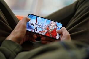 Fate Grand Order mobile iOS game on iPhone 15 smartphone screen in male hands during mobile gameplay photo